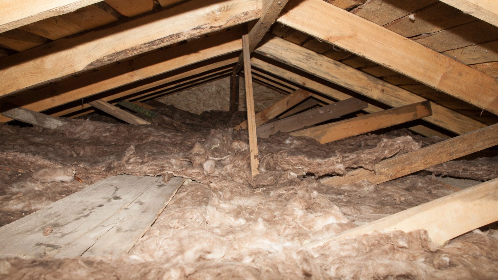 View of an attic with loose-fill insulation and wooden beams
