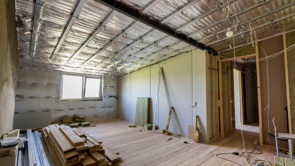 Room under renovation with insulation, drywall, and construction materials